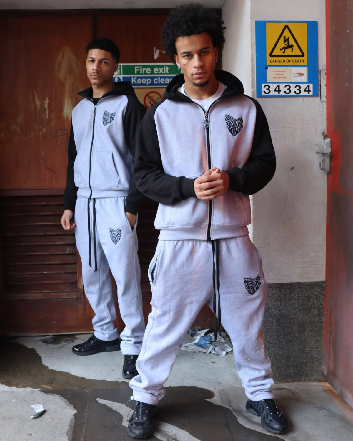 Full-length models wearing SCREWLOOSE grey and black colour-block hoodies and joggers
